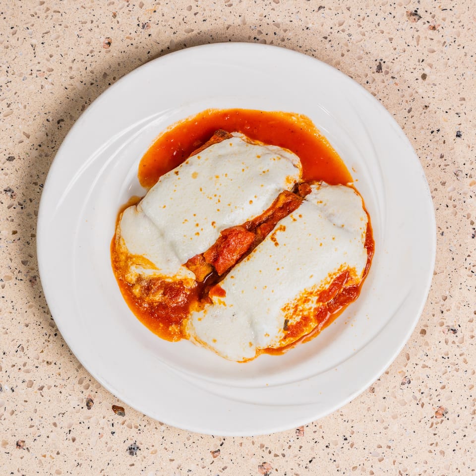 Two portions of a cheesy baked dish with red sauce, served on a white plate.
